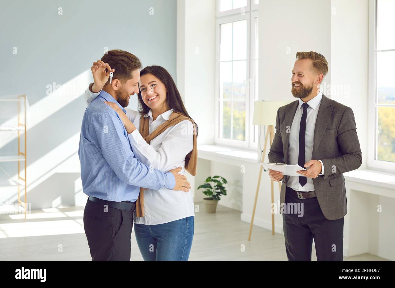 Happy young family received key to new apartment. Smiling real estate agent is happy to satisfy all the needs of clients with the purchase of property Stock Photo
