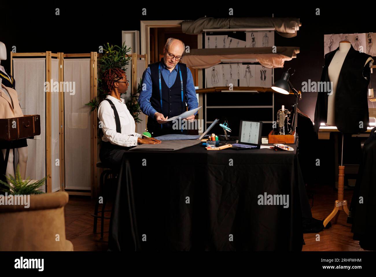 Skilled needleworker and elderly master tailor looking at handdrawn  sketches of upcoming sartorial collection. Apprentice in atelier shop  workspace helping couturier pick sartorial outfit design Stock Photo - Alamy