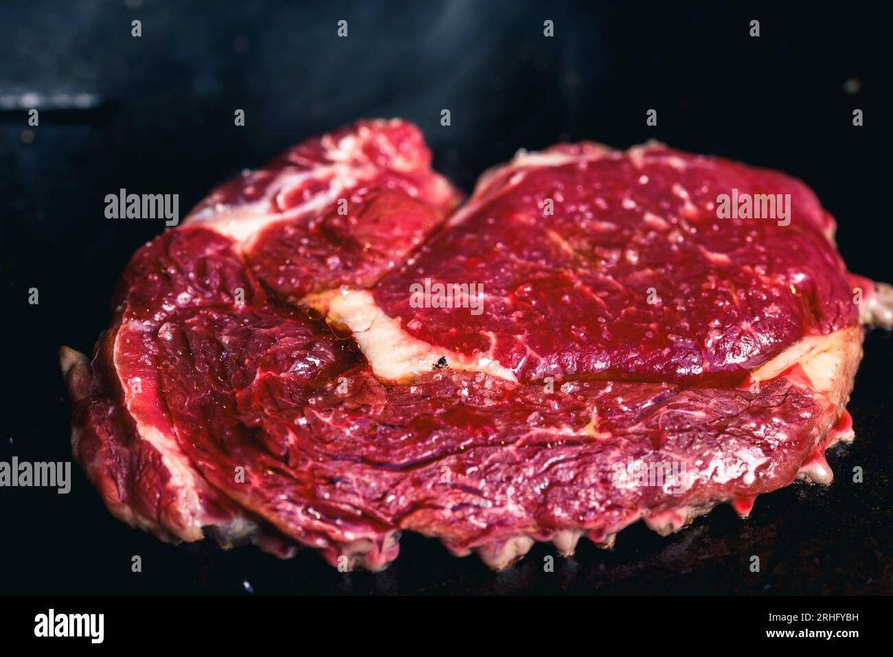 Chef cooking steak on a grill with smoke sizzling off the grill. Stock Photo
