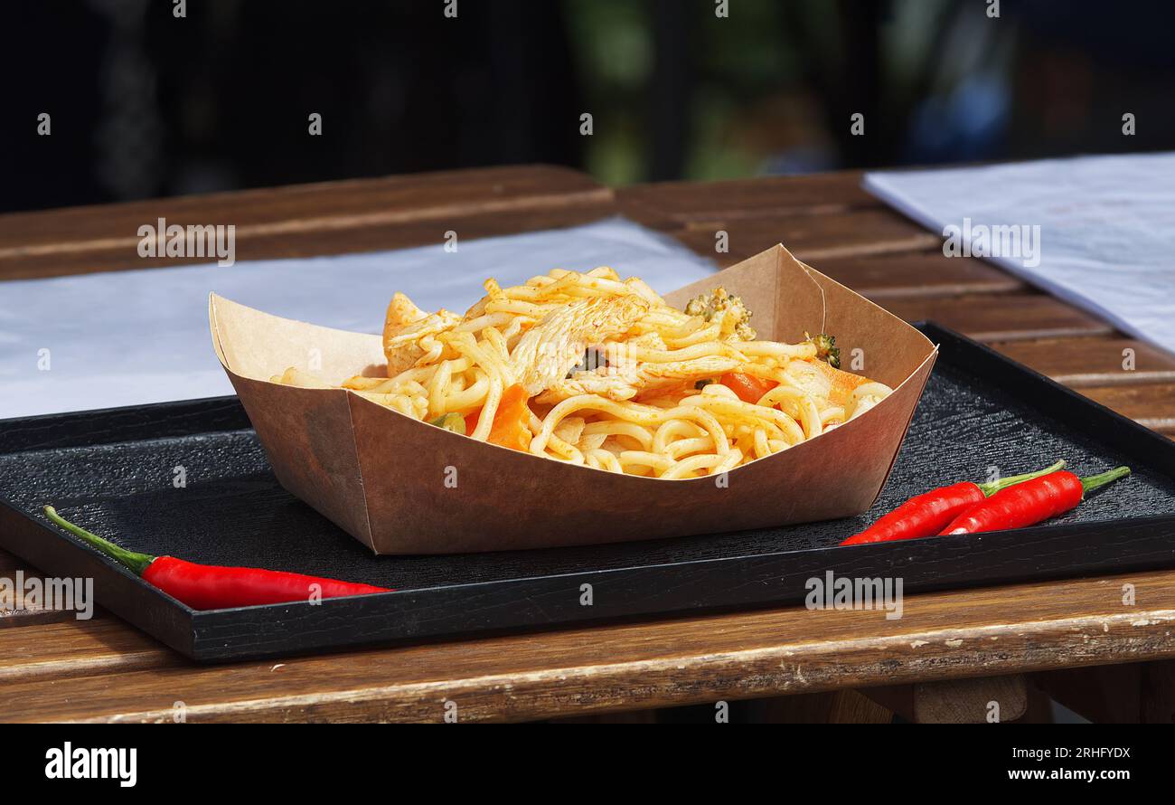 A street food market in the downtown of Prague with stall offering delicious Asian cuisine, including fried pasta noodles with chicken and vegetables Stock Photo