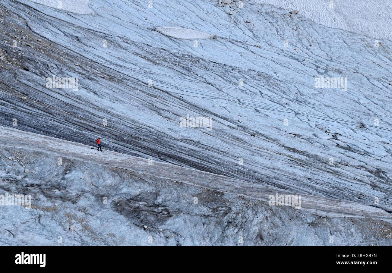 Grainau, Germany. 16th Aug, 2023. A hiker walks through the remnant snow of the Northern Schneeferner on the Zugspitzplatt. Researchers give them only a few more years: The last glaciers on German soil belong on the Red List. Credit: Angelika Warmuth/dpa/Alamy Live News Stock Photo