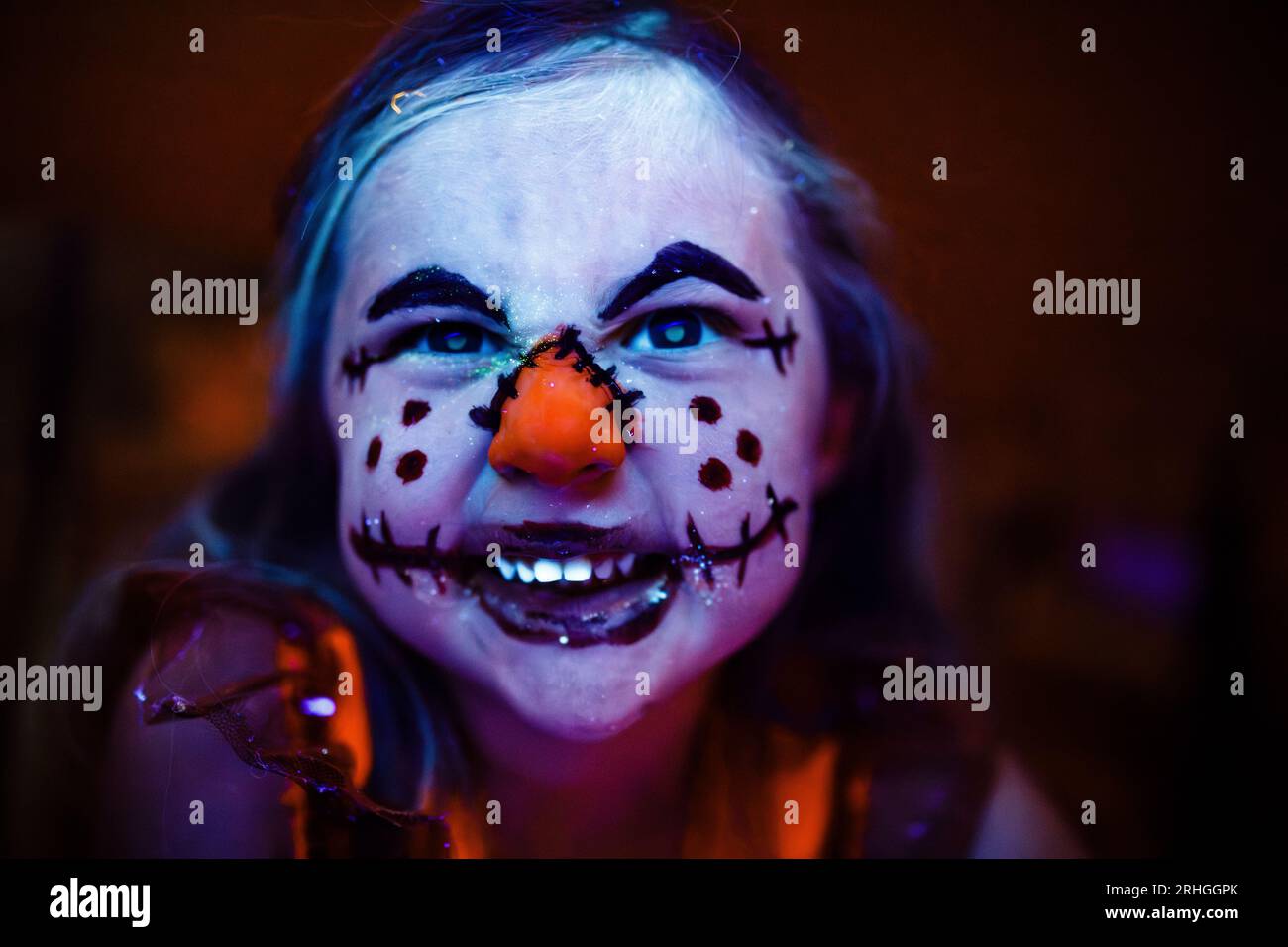 Kids Halloween scarecrow makeup face paint glowing in black light Stock Photo