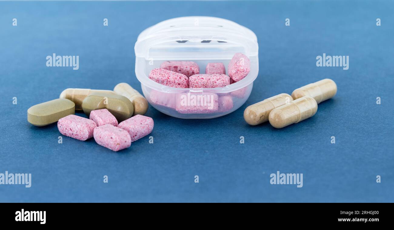 Many different pills on blue background near white organiser. The concept of taking pills according to some schedule, plan, prescription. Stock Photo
