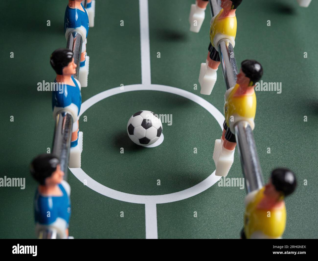A closeup of some players and a soccer ball on a foosball table. Board