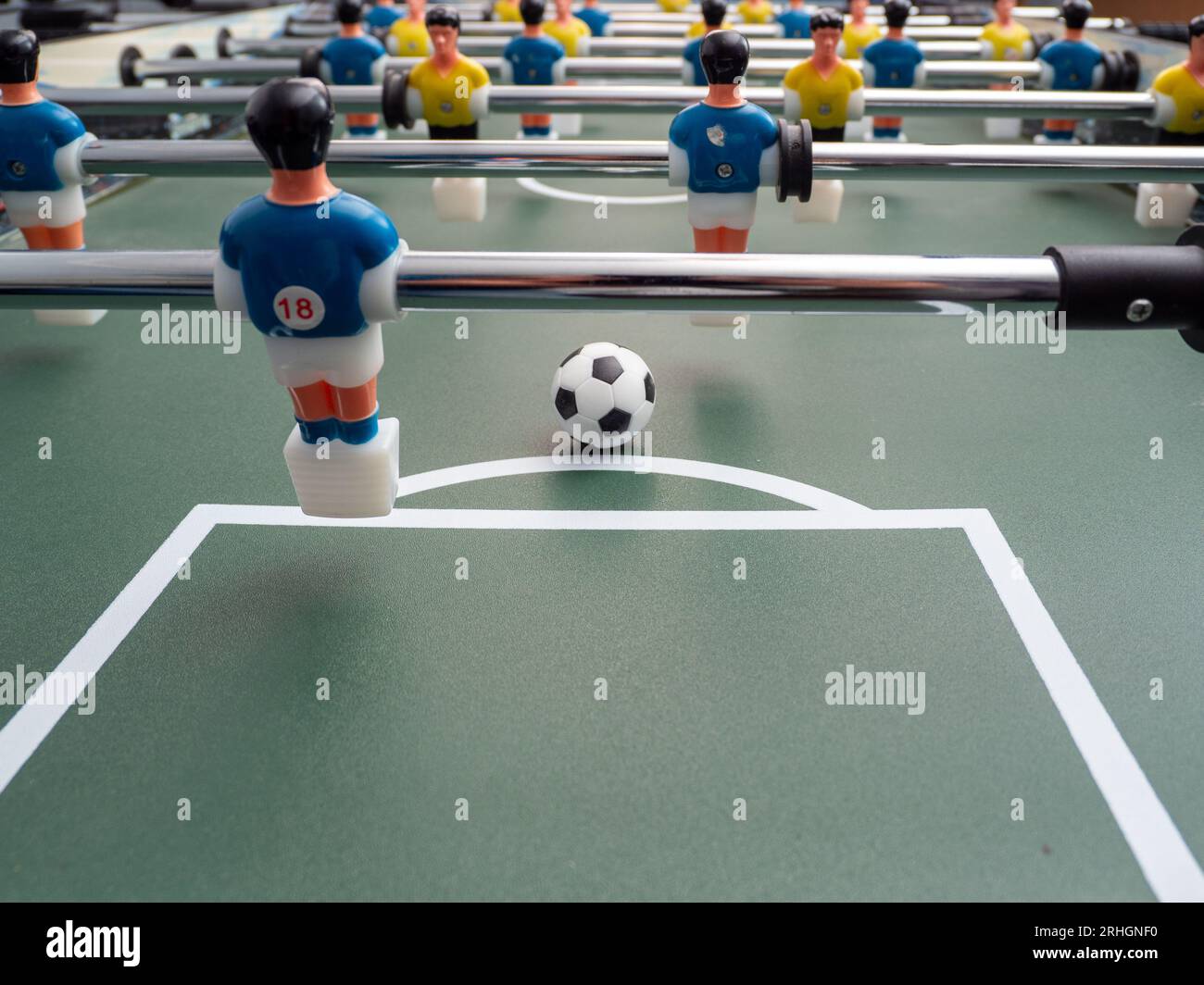 A closeup of some players and a soccer ball on a foosball table. Board