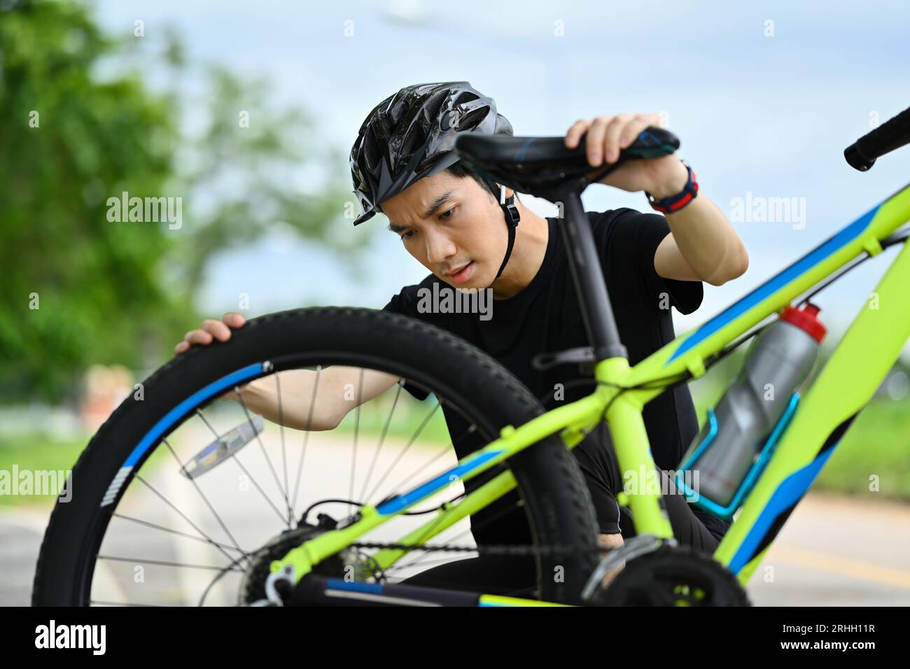 Concentrated male cyclist checking tire or transmission system of his ...