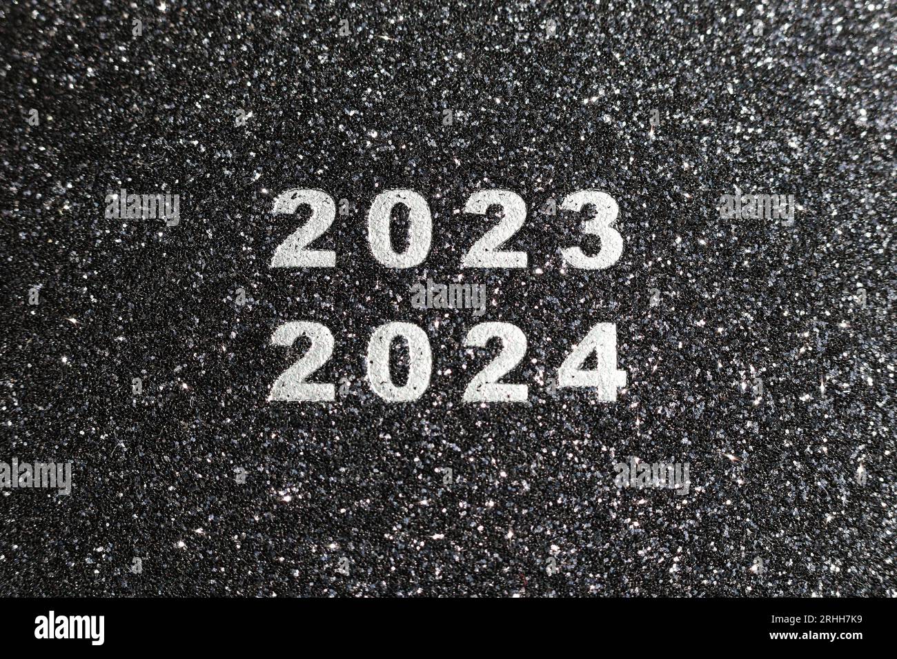2023 and 2024 printed on a black glitter texture background Stock Photo