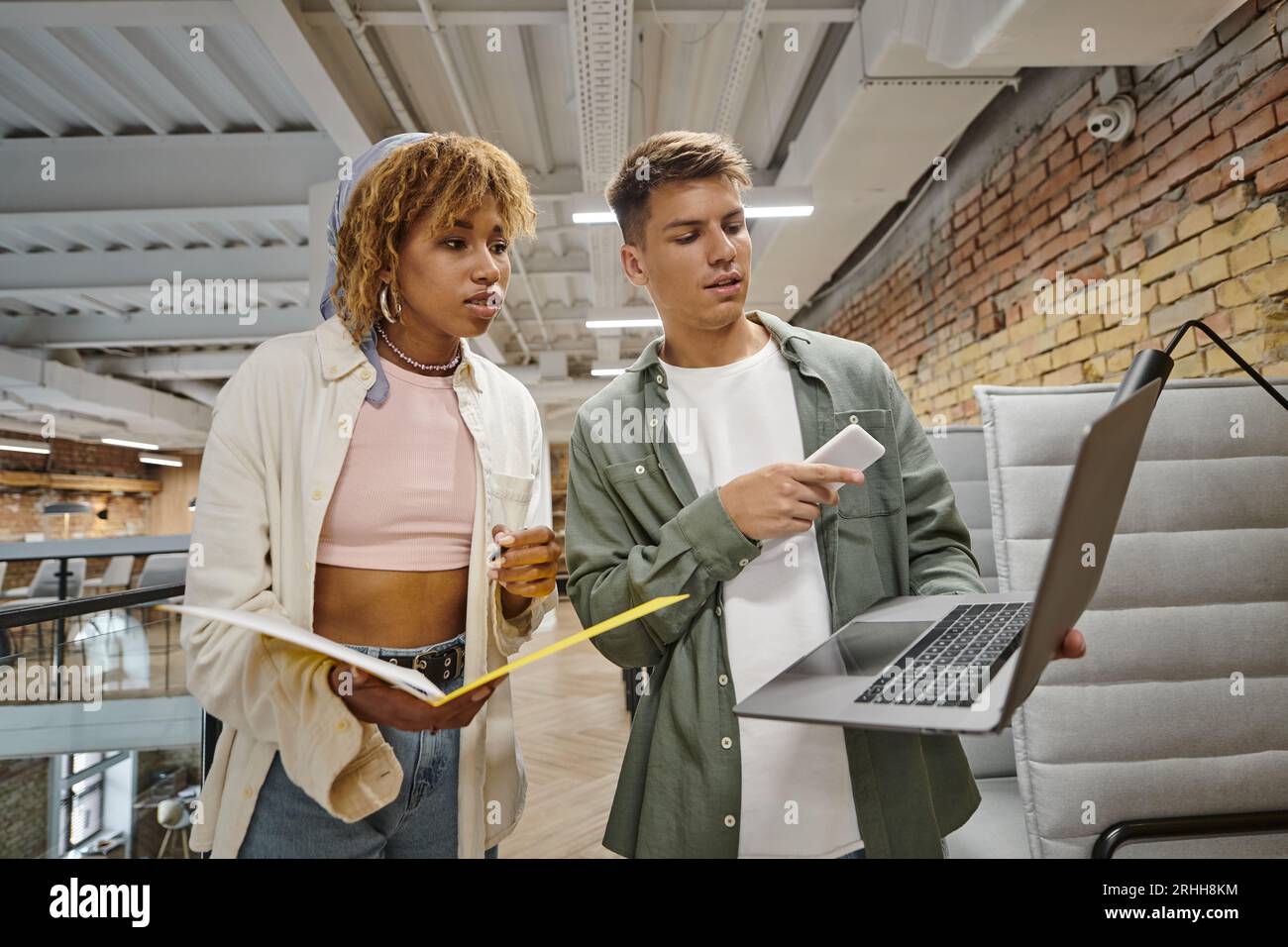 young man showing project on laptop to african american woman, startup, planning, ideas, gen z Stock Photo