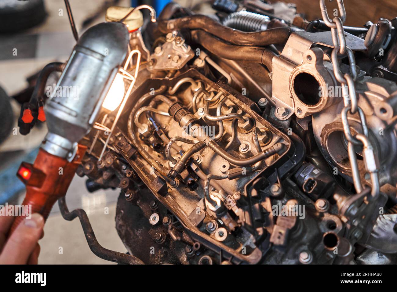 A car mechanic inspects the engine with a flashlight. Engine Block on a