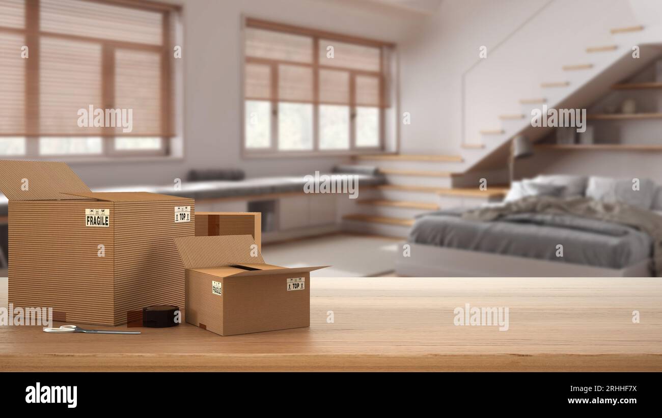 Wooden table, desk or shelf with stack of cardboard boxes over blurred view of bedroom with staircase, modern interior design, moving house concept wi Stock Photo
