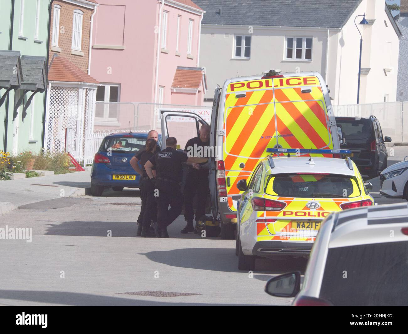 Several Police officers accompanied by sniffer dog are seen making a forced an entry to a house located on  Stret Kosti Veur Woles. This location is in the King Charles project model village on the outskirts of Newquay. An eye witness reported the front door was broken down to gain access. A number of individuals were seen being escorted by police officers. Devon and Cornwall Police make a drug related raid. Nansledan  Cornwall  UK. 17th August 2023. Robert Taylor Stock Photo