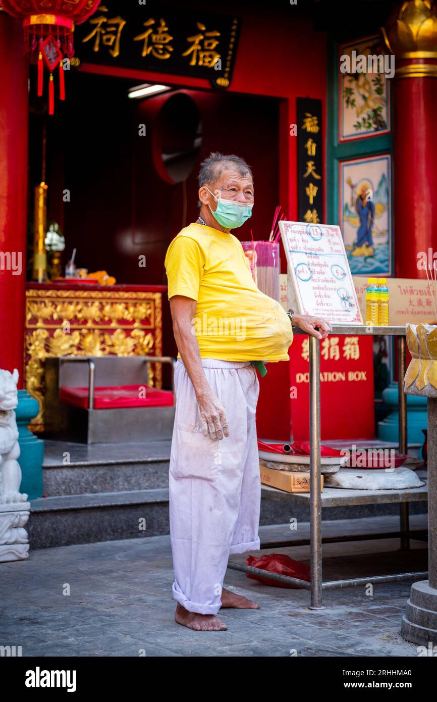 An old Thai man stands outside a Chinese Temple in China Town, Bangkok, Thailand. Stock Photo