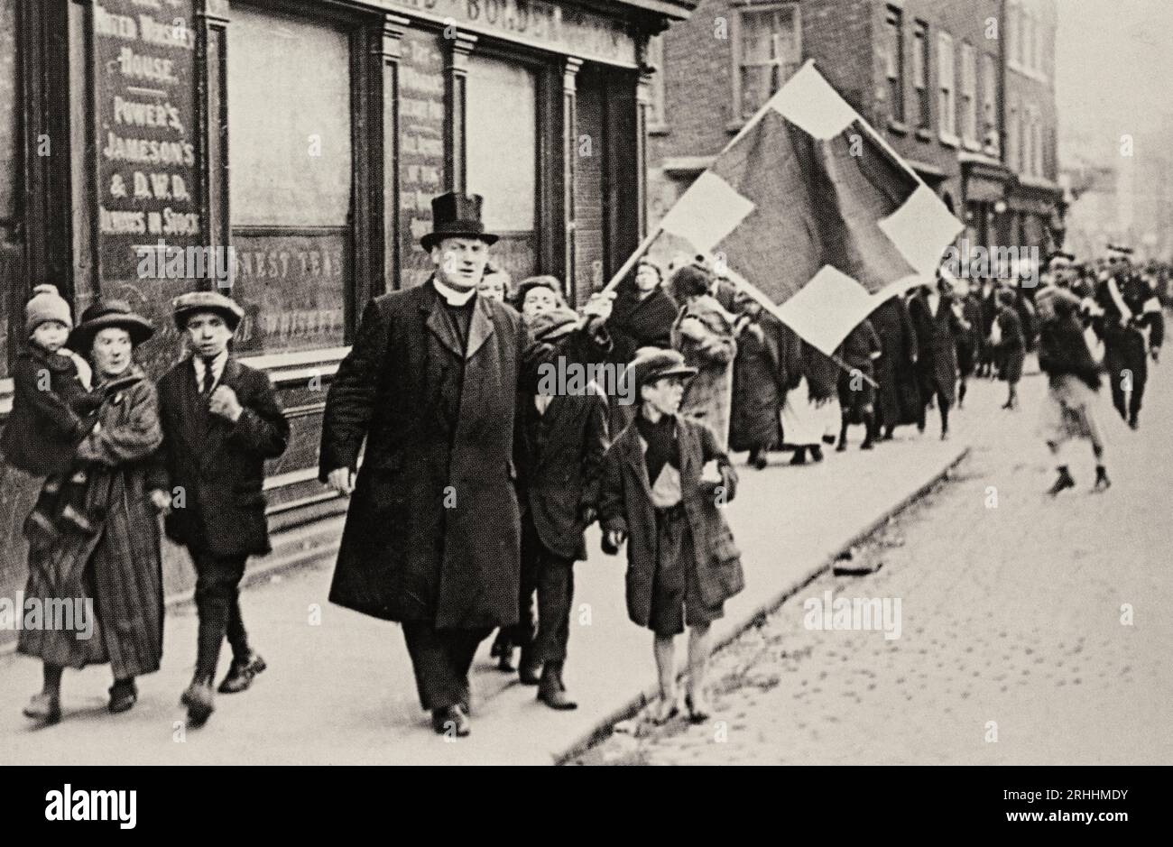 An early 20th century photograph shot during the Civil War (1922-23) of a priest waving a Red Cross flag, in the hope it would safeguard children making their way to school in Dublin. Stock Photo