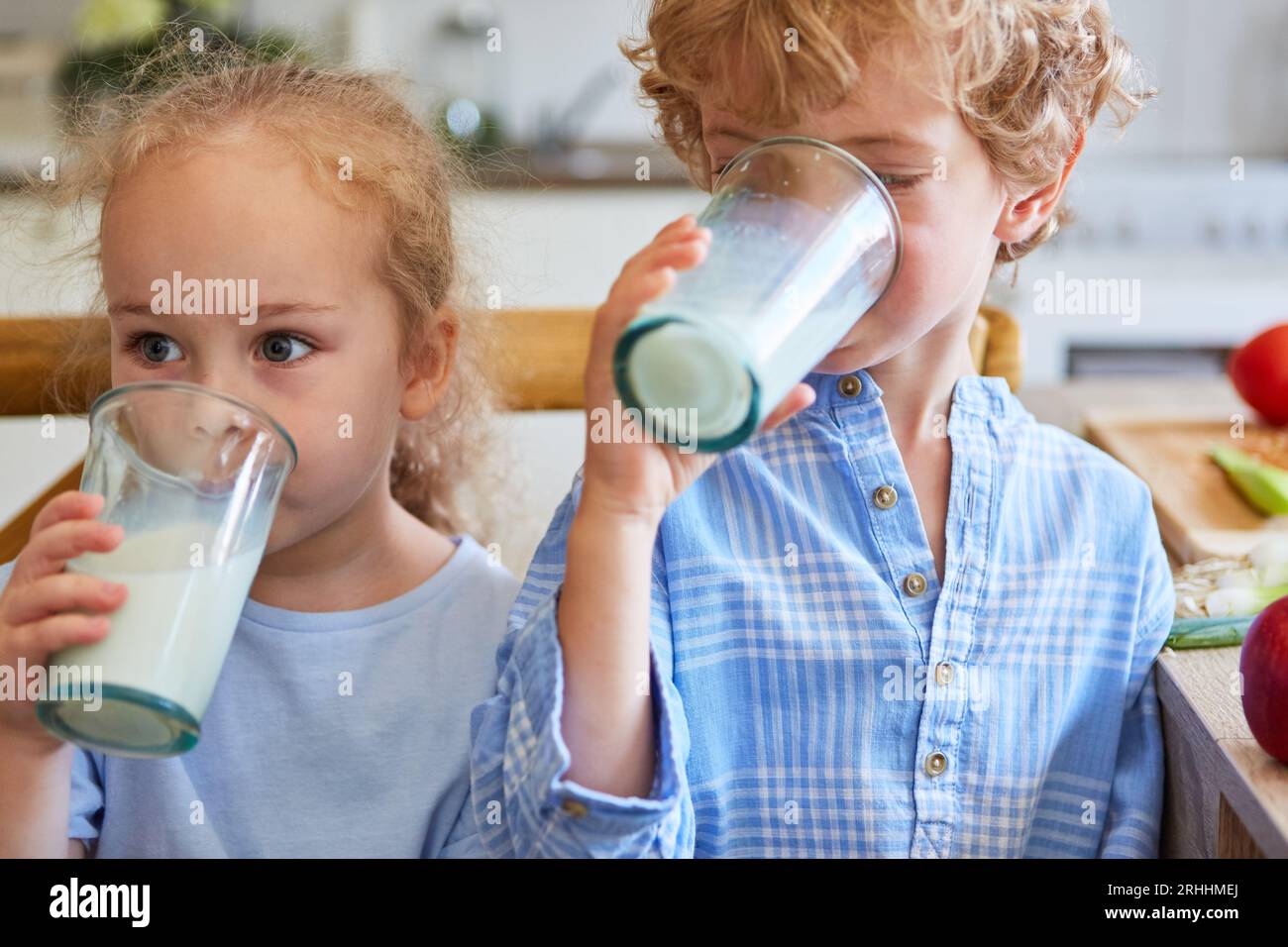 Sister drinking milk with brother in kitchen at home Stock Photo Alamy