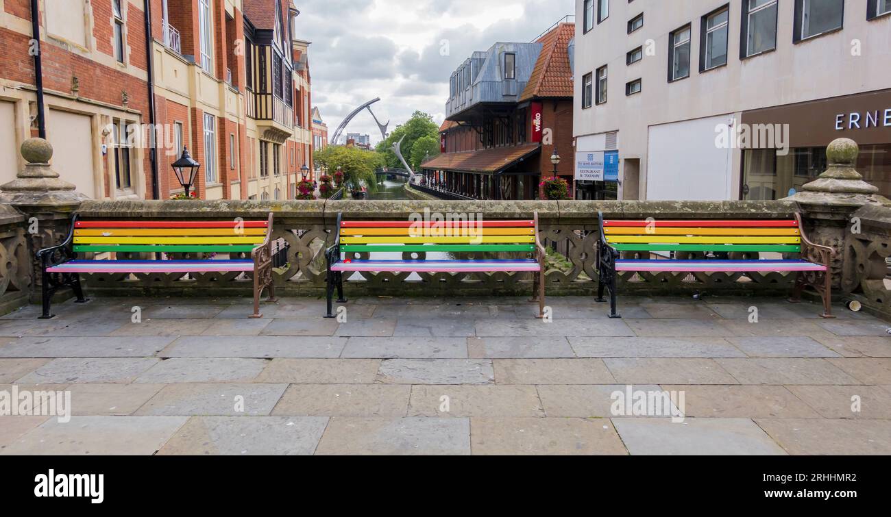 Three bench seats in Pride colours on High Bridge, High street, Lincoln City, Lincolnshire, England, UK Stock Photo