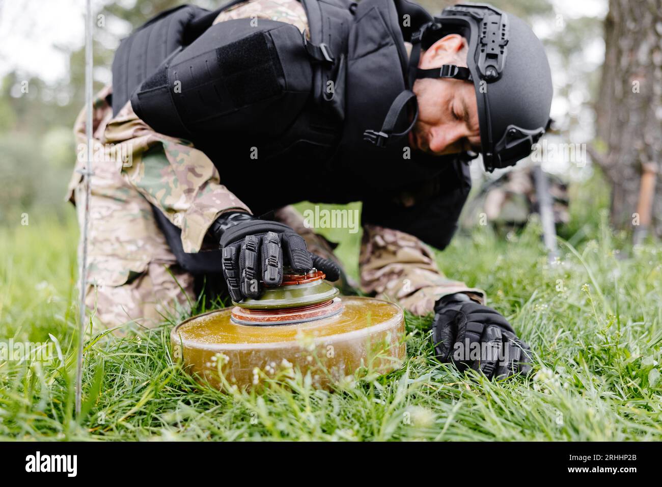 A man in a special suit works with a detector and found an explosive device. A man tries to neutralize an anti-tank mine. Stock Photo