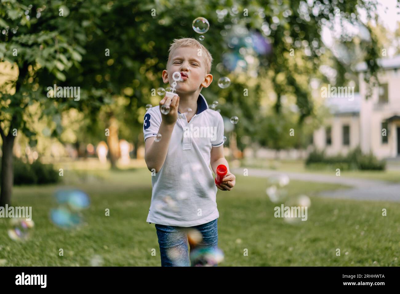 cute caucasian blond boy blowing soap bubbles in park. High quality photo Stock Photo