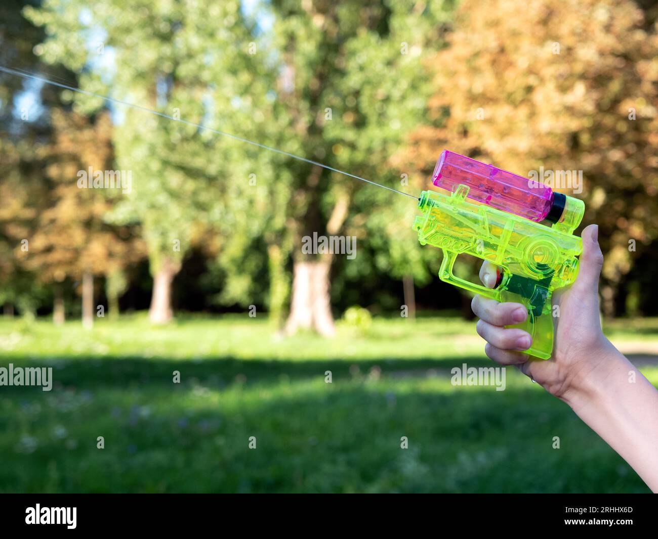 Child is shooting jets of water using a water gun or squirt gun toy, selective focus and copy space. Summertime kids leisure Stock Photo