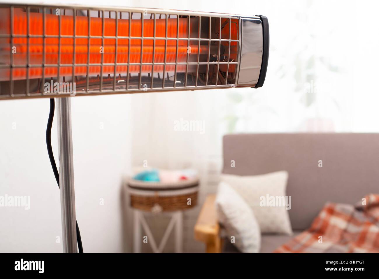 Electric infrared heater warming up living room with sofa and potted