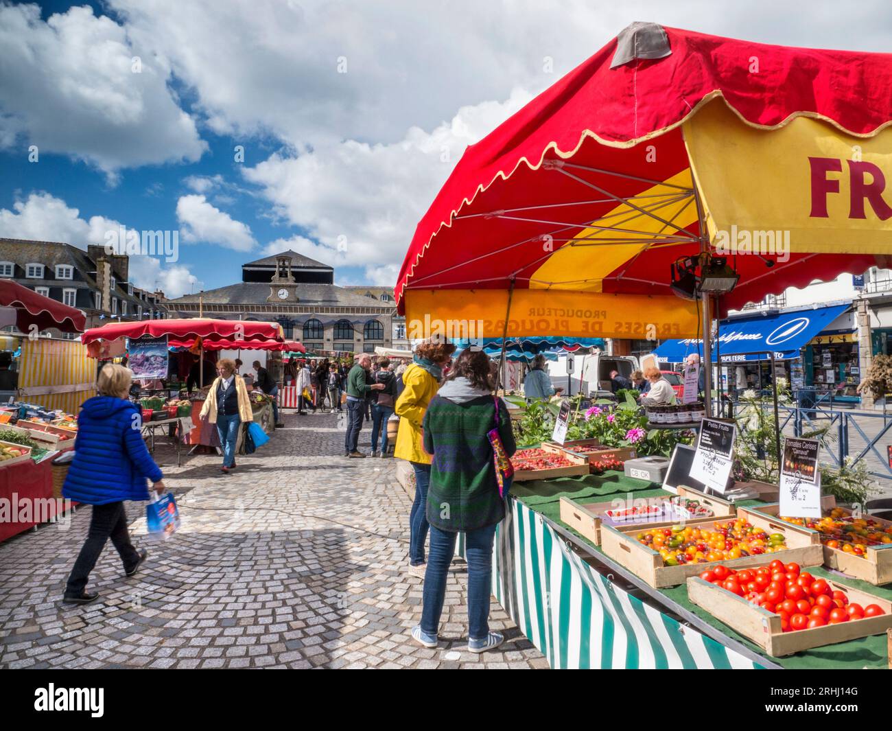 CONCARNEAU MARKET BUSY OUTDOOR Fresh French Produce on display market day in square with covered market in background Concarneau Brittany France Stock Photo