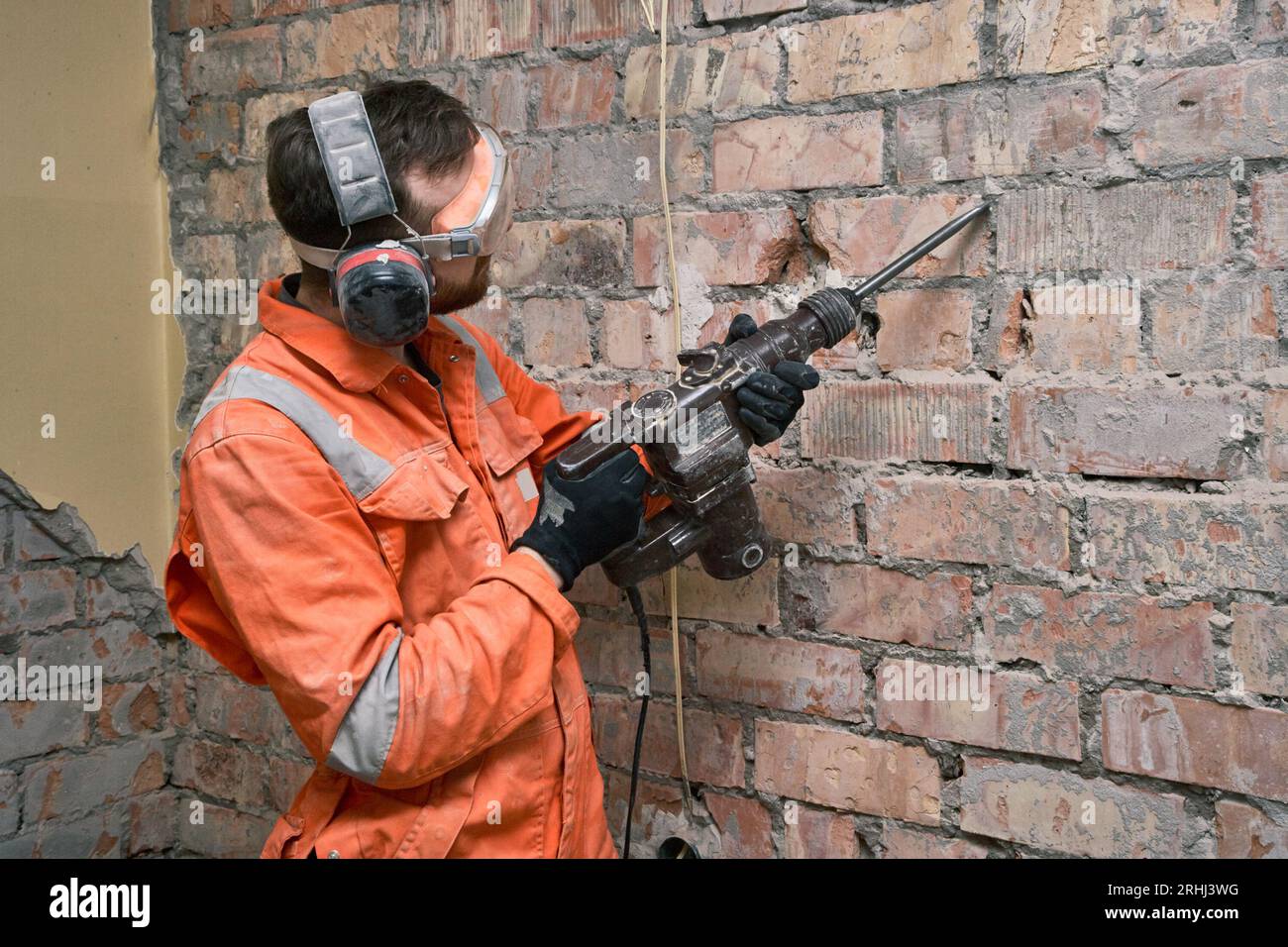 Construction worker using hammer drill with chisel to remove old cement