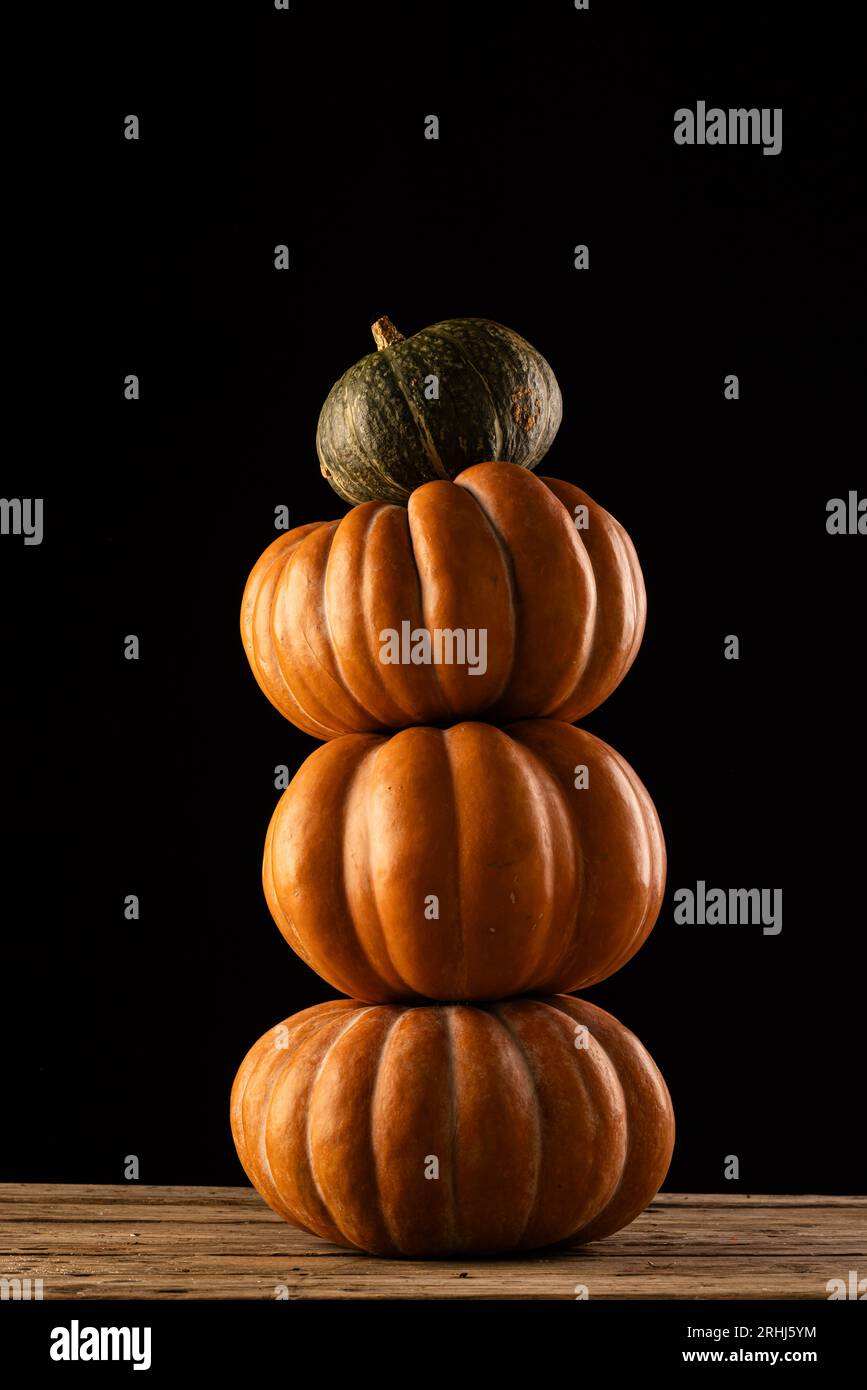 Orange and green pumpkins stacked up with copy space on black ...