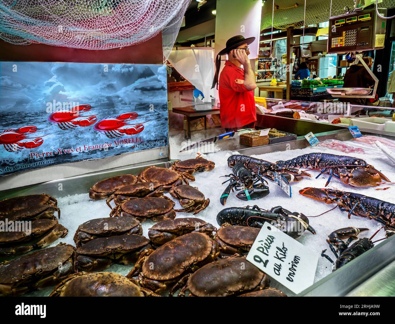 FRENCH LOBSTER CRAB FISH MARKET CONCARNEAU with Breton character traditional fishmonger checking on an incoming fresh catch. Daily Fish Market hall with 'High Season' fresh crab and blue lobster on display for sale.LES HALLES FISH MARKET CONCARNEAU Brittany France Stock Photo