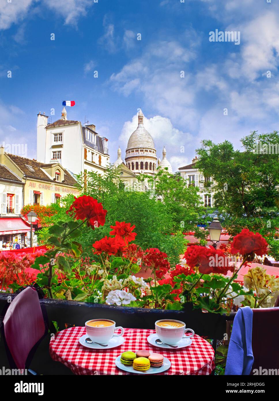 Paris Café Restaurant Coffee Cups View Vista Montmartre spring summer flowers coffee for two and small cakes macaroons on french checkered tablecloth with floral view. French tricolour flag flying, overlooking Place du Tertre, Sacre Coeur behind Montmartre Paris France Stock Photo