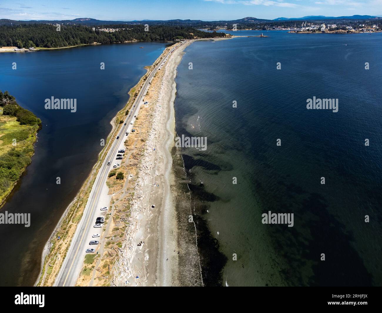 Aerial sand spit with a long straight road with people on vacation and cars parked in Victoria British Columbia Canada. Stock Photo