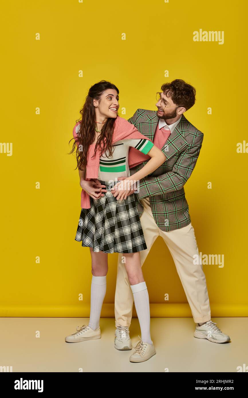 cheerful couple having fun, man in glasses and young woman looking at each other, hug, students Stock Photo