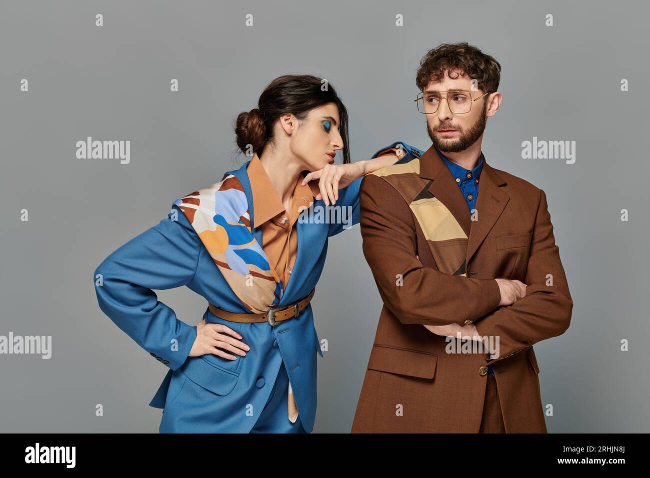 stylish man and woman posing in tailored suits, formal attire, grey ...