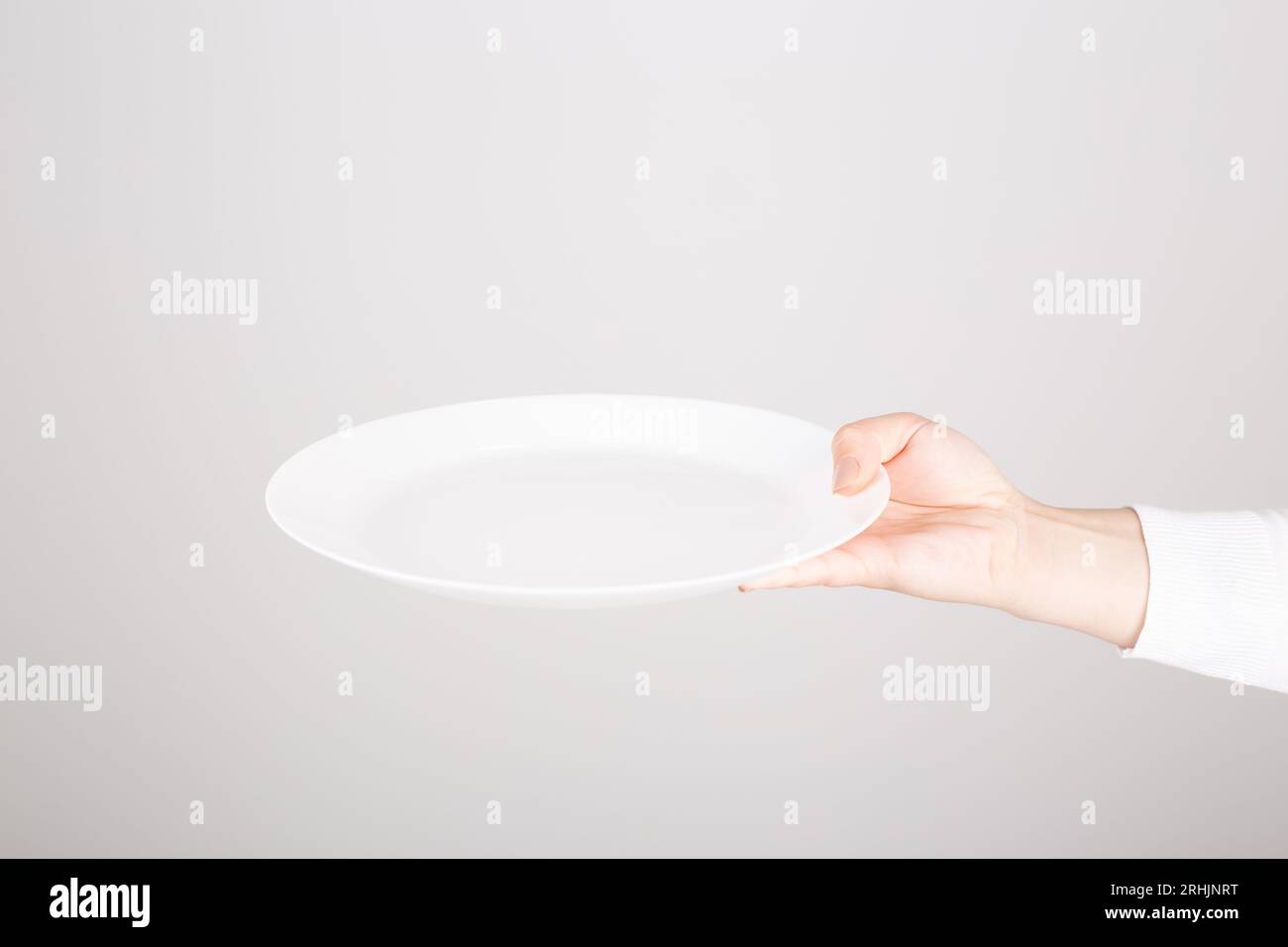 a female hand holding an empty white plate Stock Photo