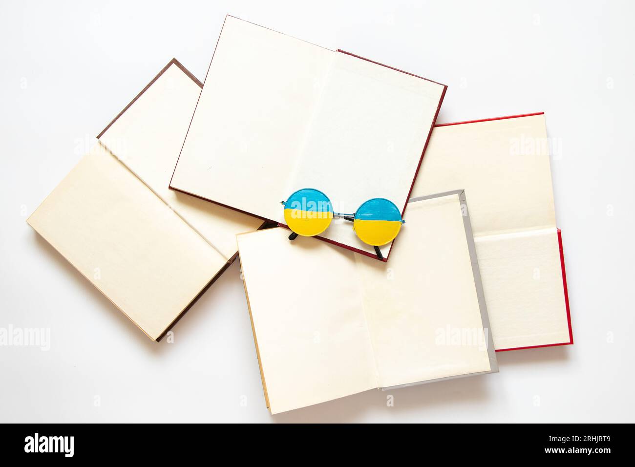 The flag of Ukraine is drawn on glasses that lie on open books on a white background, education in Ukraine Stock Photo