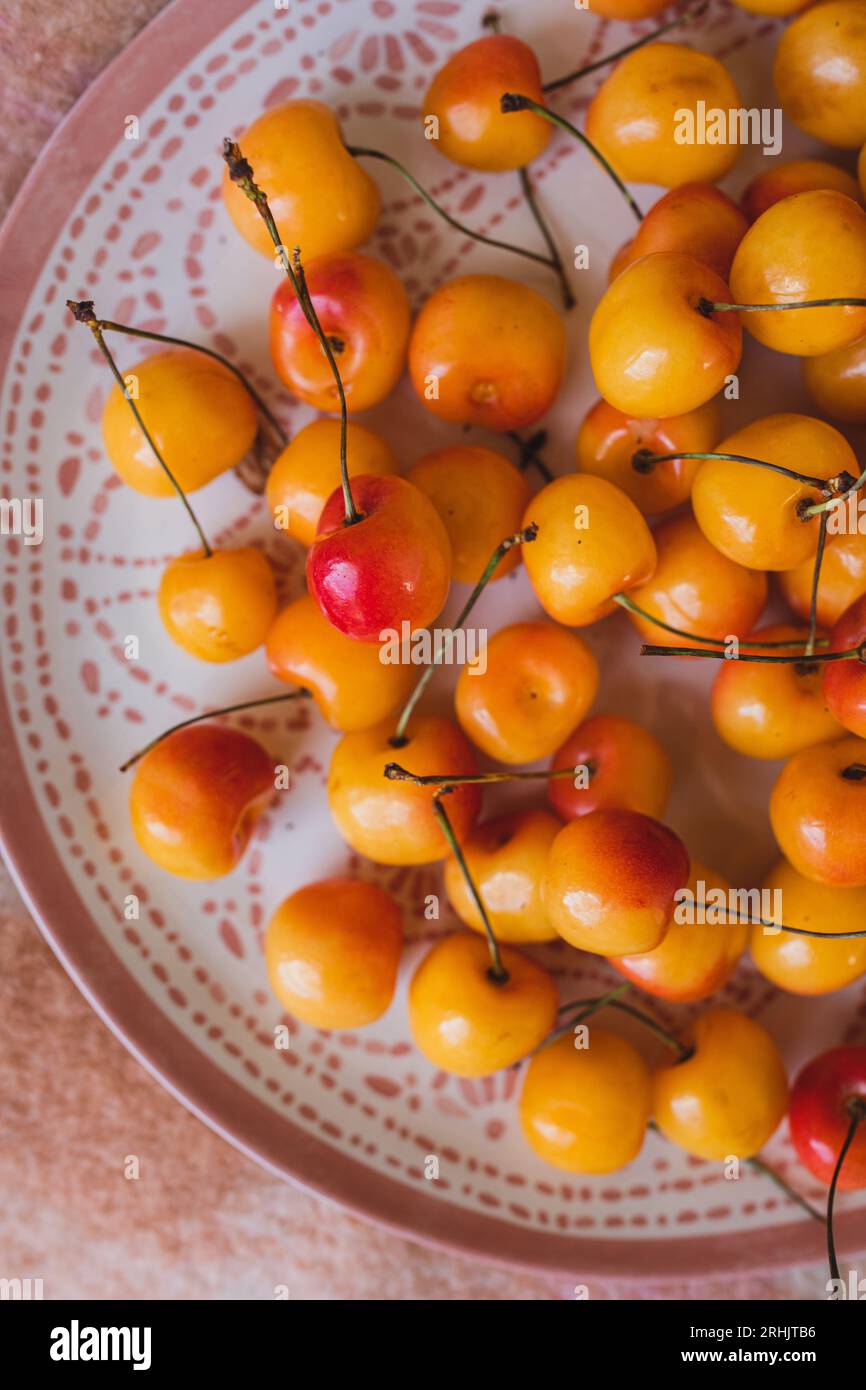 platter, plate full of yellow, red Rainier cherries on pink picnic blanket Stock Photo