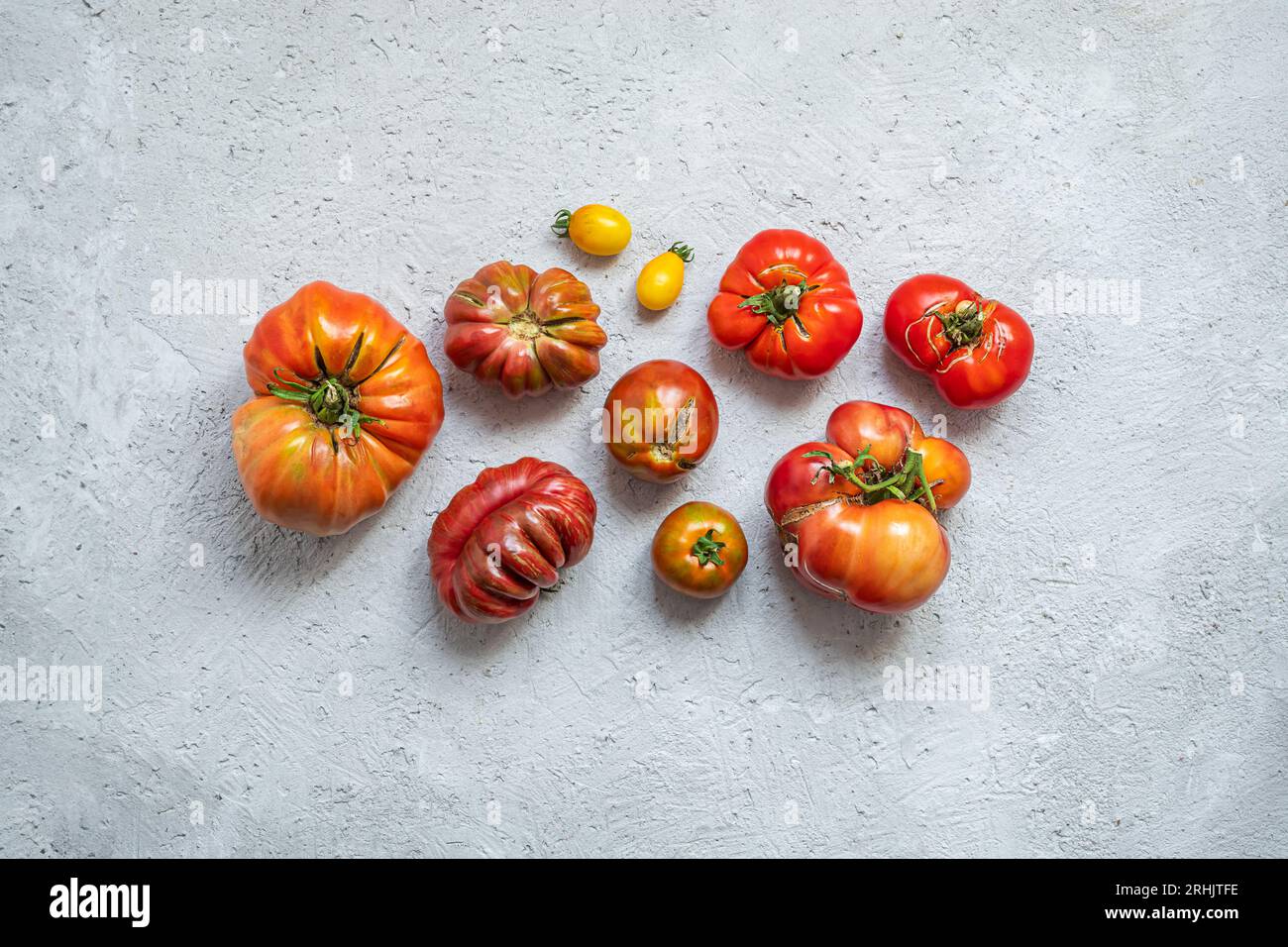 Ugly organic untreated tomatoes on the gray background. Food waste concept Stock Photo