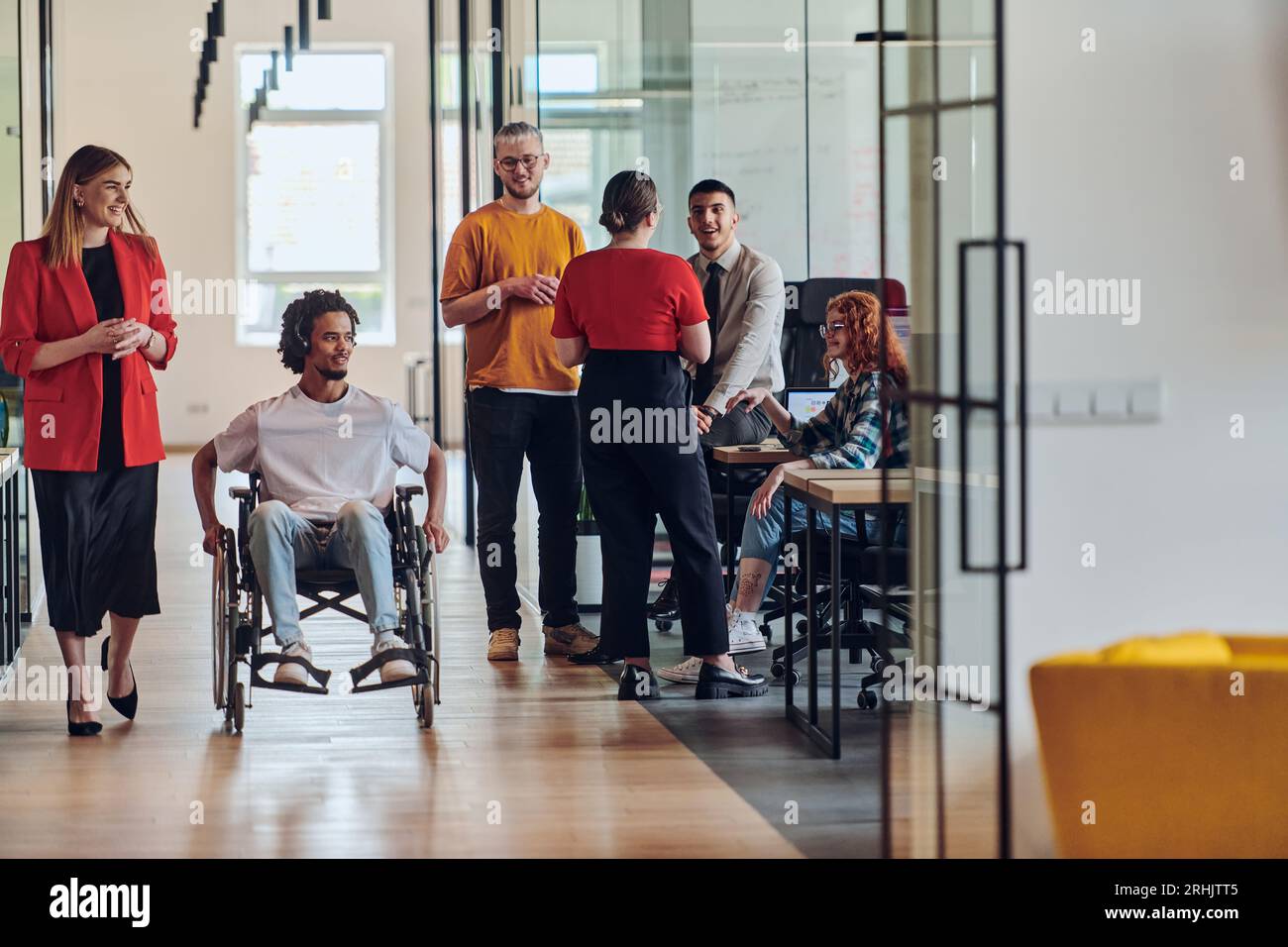 A group of young business people in a modern glass-walled office ...