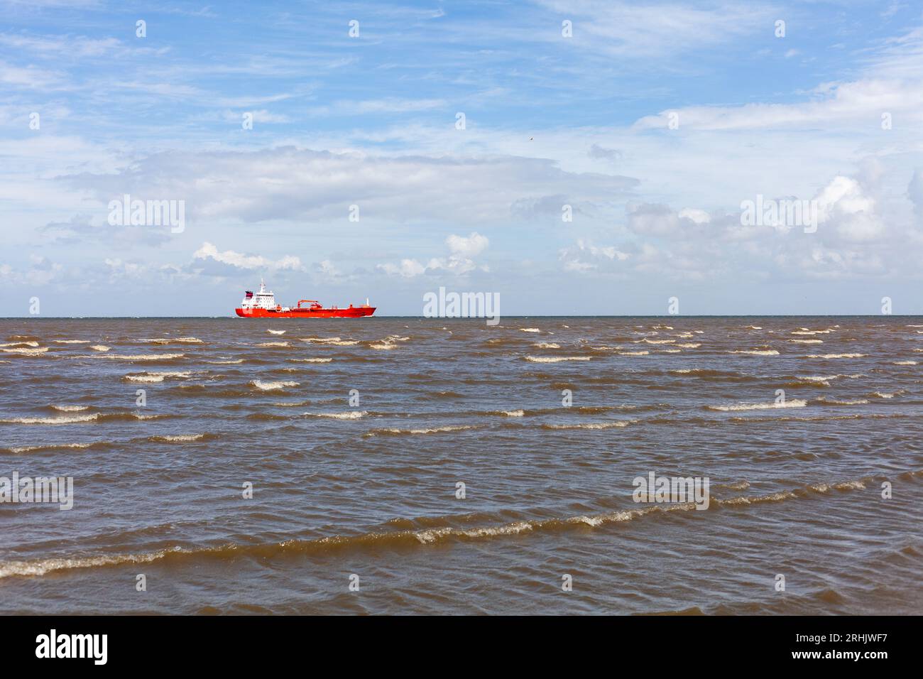 Red boat in the sea on a background of blue sky with clouds Stock Photo ...