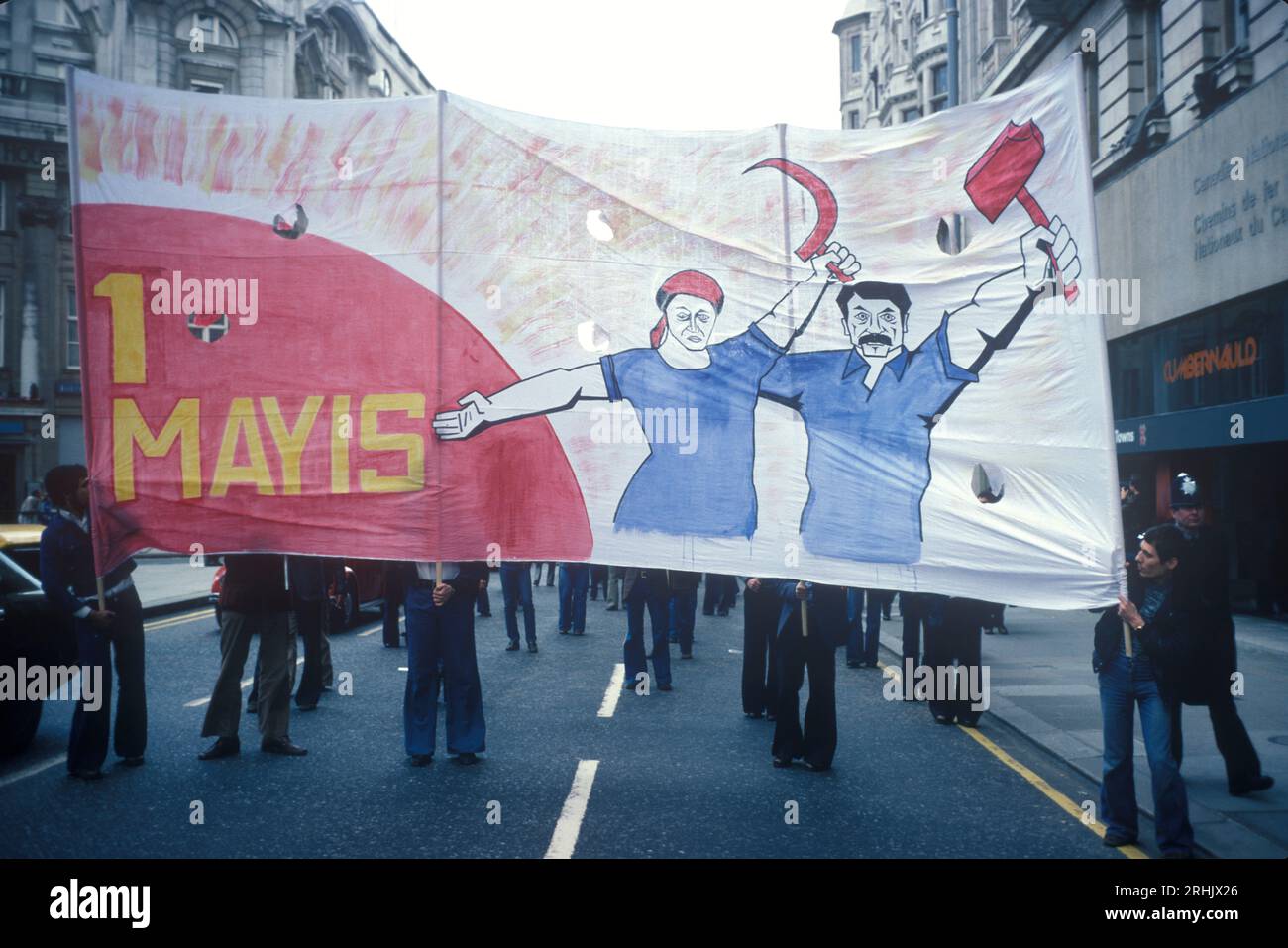 May Day March 1970s UK. International Workers' Day, also known as Labour Day  Hugh banner depicting a man and woman with a Hammer and Sickle, from the East End London to Hyde Park. London UK May 1977 HOMER SYKES. Stock Photo