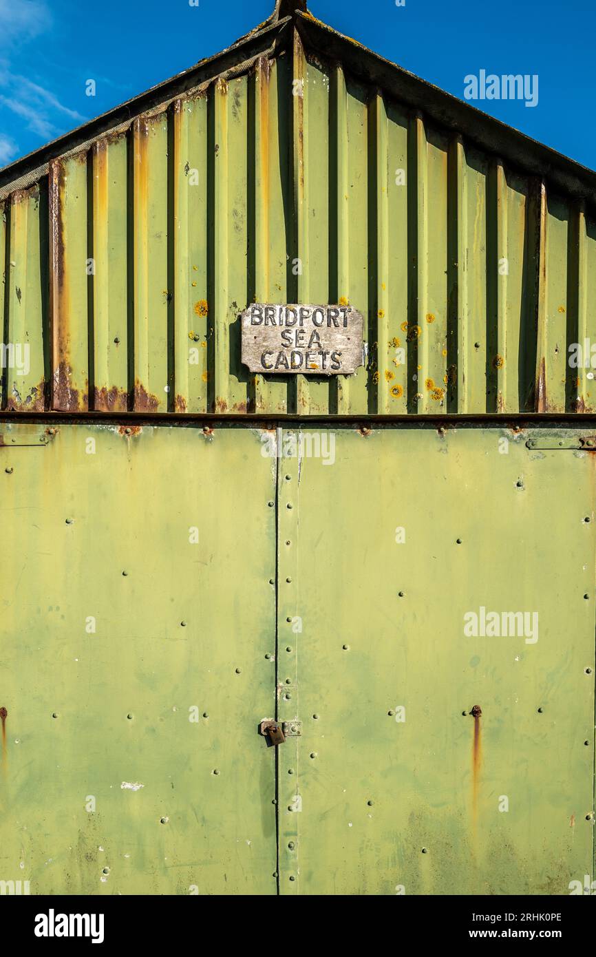 Abstract image of old metal building painted green with rust and shades, Sea Cadet sign on the outside. Colourful abstract. Textures. Rusty. Stock Photo