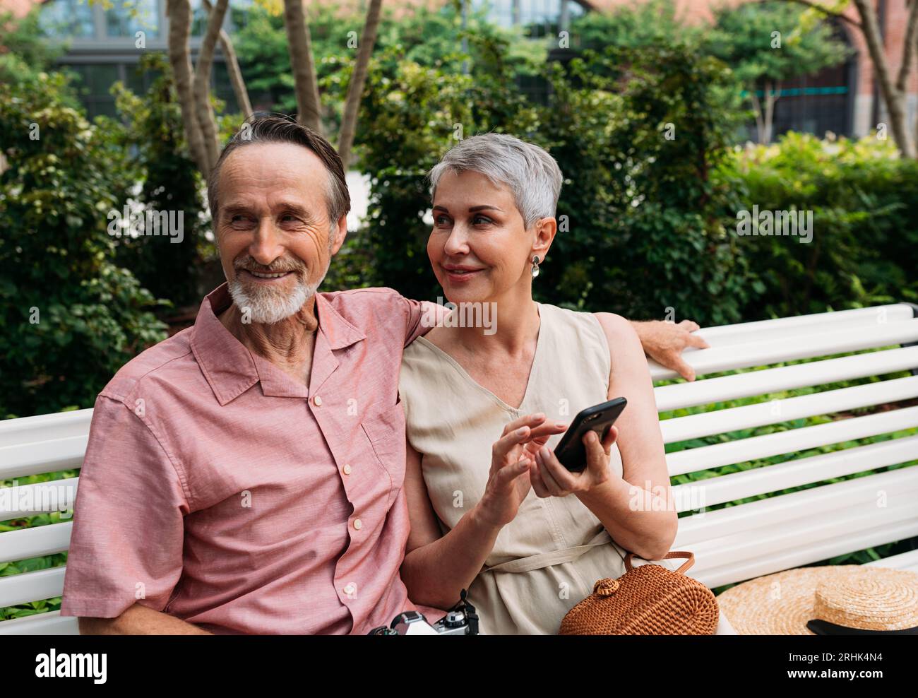 Smiling retired couple sitting on a bench in a park Stock Photo