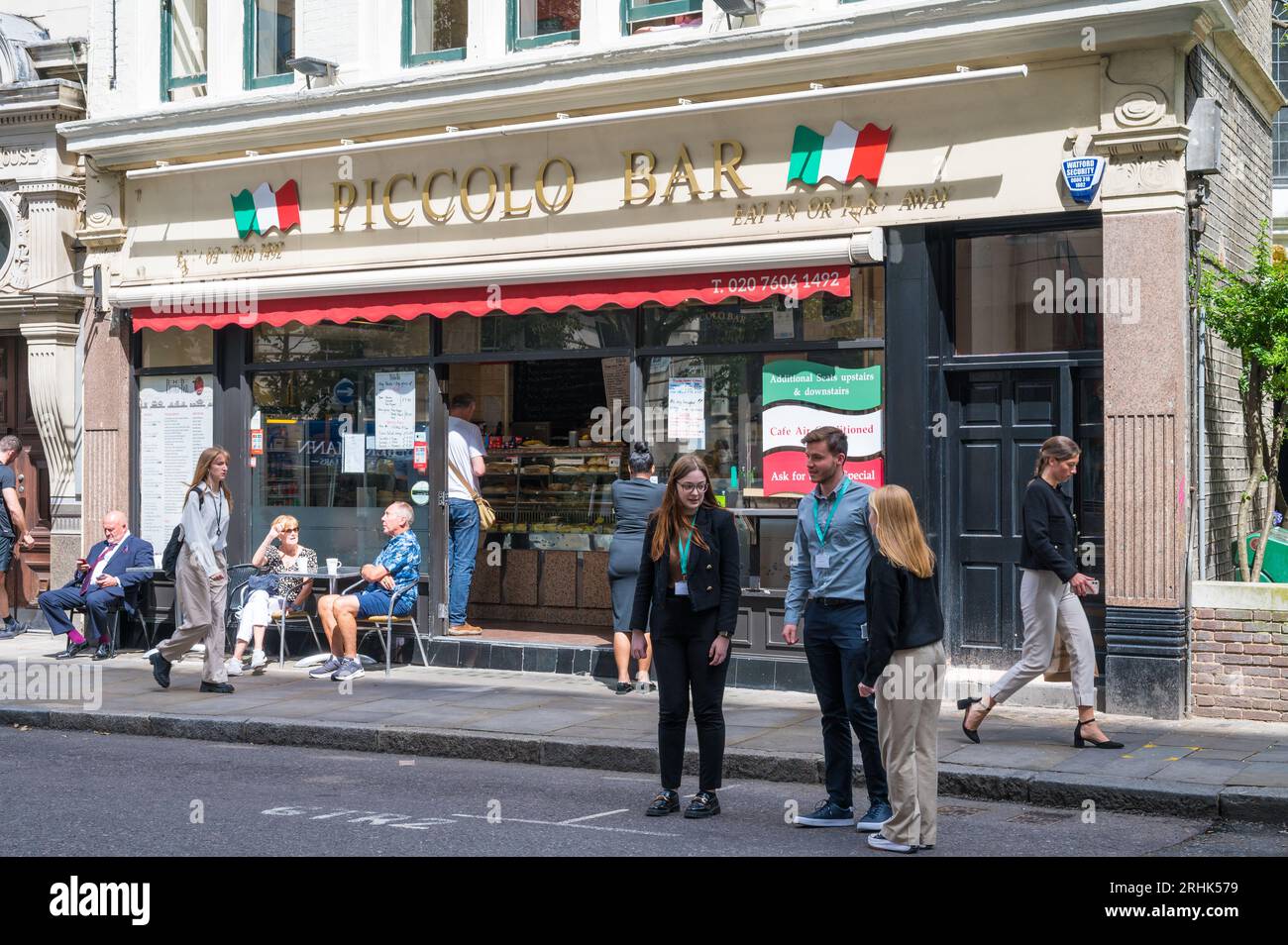 Exterior facade of Piccolo Bar. Italian bar and cafe on Gresham Street, City of London, England, UK. People walk by, others seated at pavement tables. Stock Photo