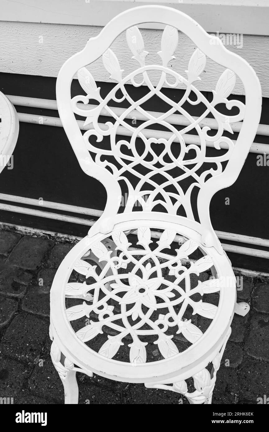 Victorian style white empty metal chair in outdoor cafe. Wrought iron furniture, old fashion cozy cafe terrace, at an outdoor terrace. Sidewalk cafe. Stock Photo