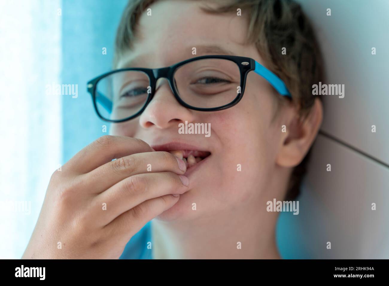 portrait of a happy boy with glasses who eats cherries and smiles. A cheerful child at home among the family. Happy carefree childhood. Stock Photo