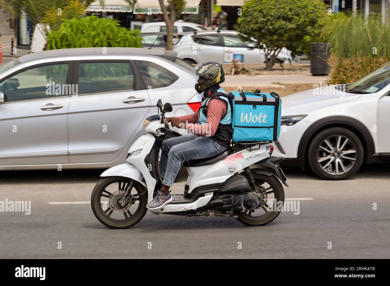 Sliema, Malta - 6 August 2023: Person riding a motor scooter with an Insulated container for the Wolt food takeway delivery service on the back Stock Photo