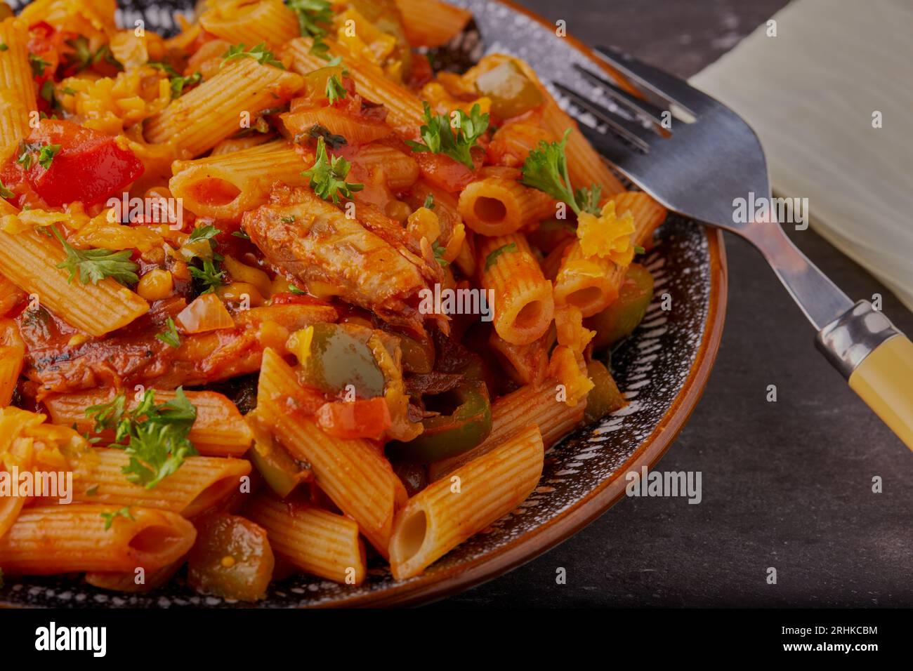 Sardines and pasta with vegetables and a tomato sauce, garnished with herbs. Stock Photo
