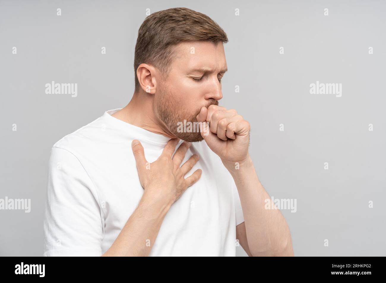 Portrait of man has bad cough, sore throat,chest pain on grey