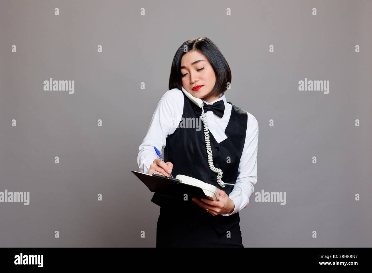 Waitress with clipboard talking on landline phone, managing restaurant