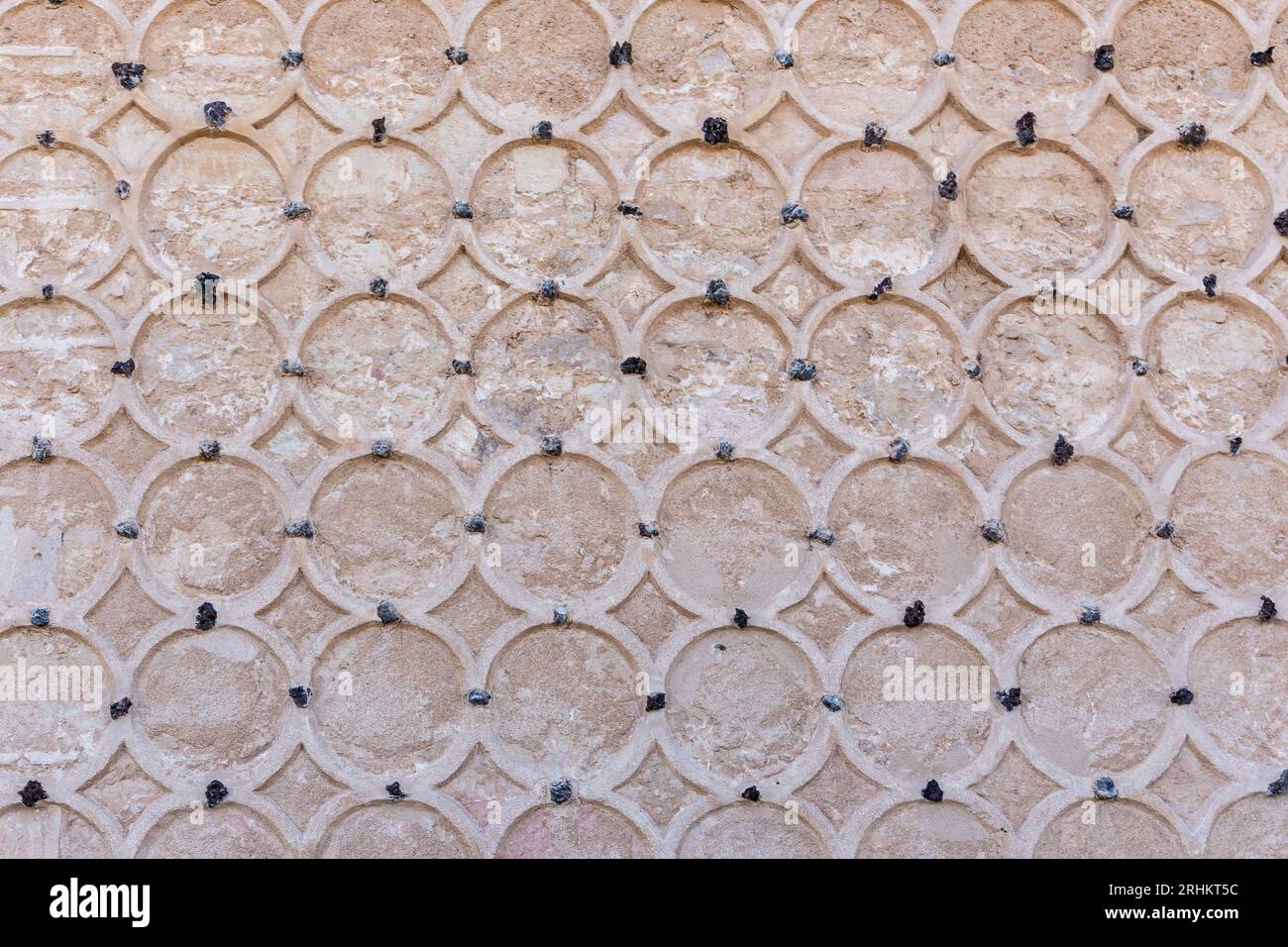 Ornamental stone facade of the Alcazar of Segovia, Spain. Islamic ornaments with circular sgraffito motifs, carved circles on stone wall. Stock Photo