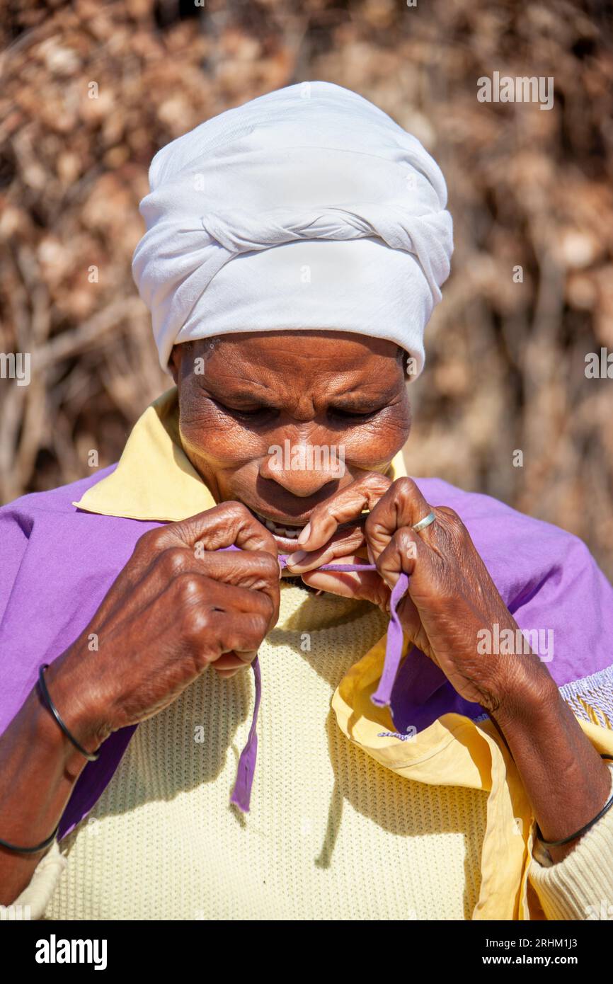 african woman in the village standing in the backyard arranging her church uniform Stock Photo