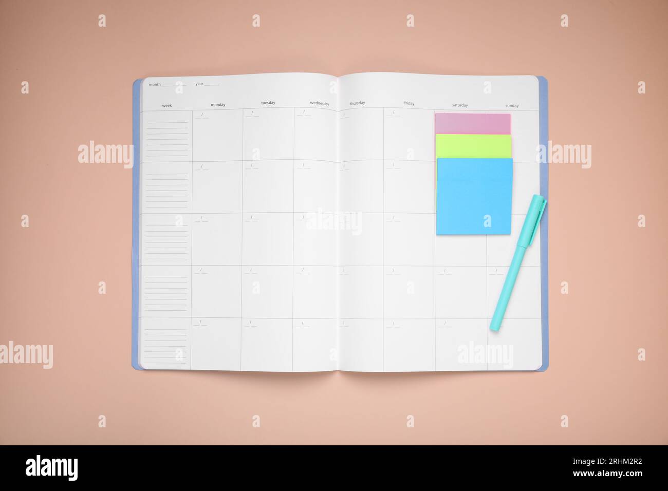 Open monthly planner, blank sticky notes and pen on beige background ...